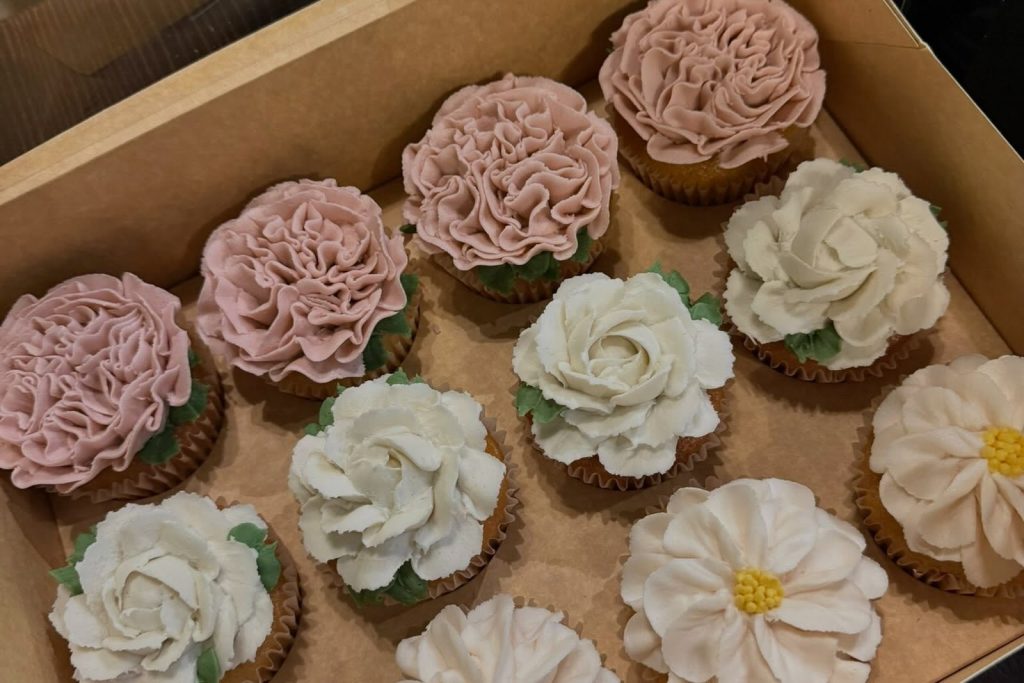 Box of cupcakes with piped buttercream roses, carnations and daisies
