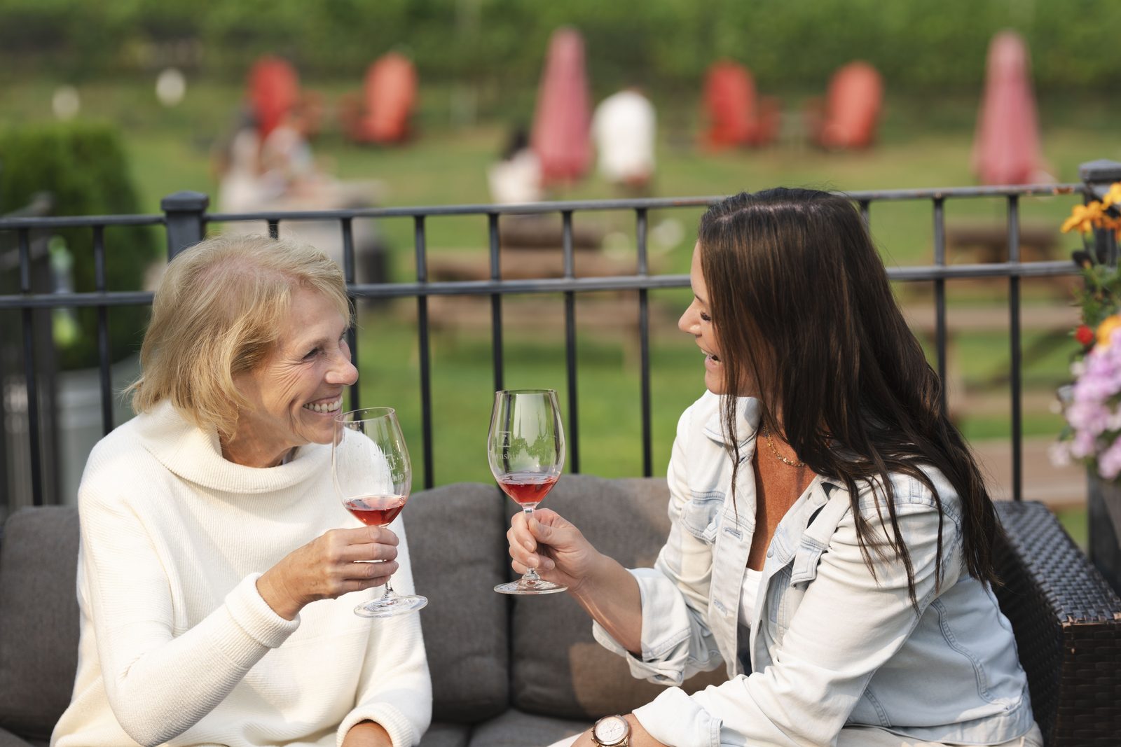 Two friends toasting with glasses of rosé on a Langley winery patio